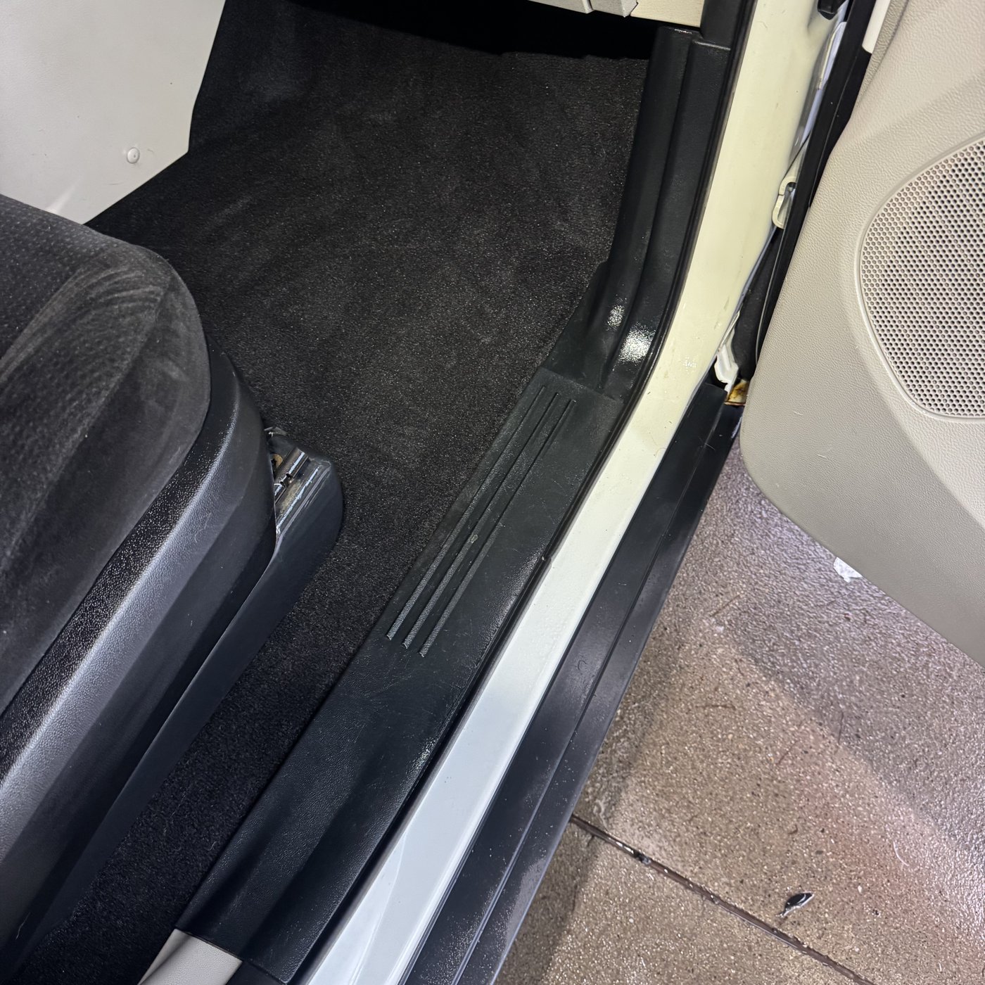 The matching footwell after detailing, with clean black carpet and a freshly cleaned door sill